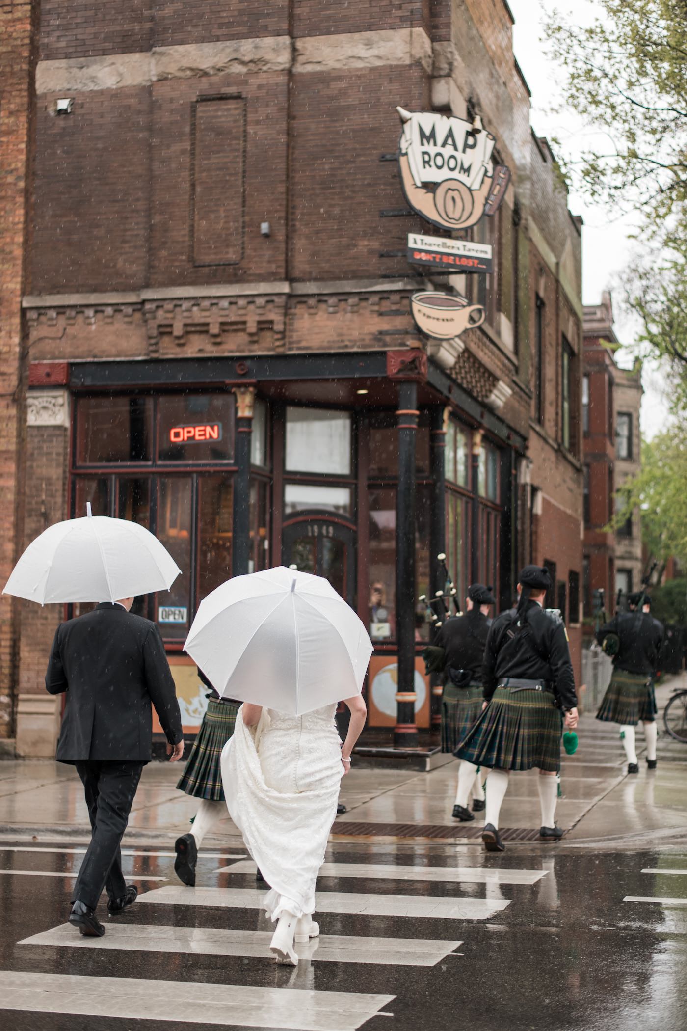Bride and groom cross the street with white umbrellas in Chicago